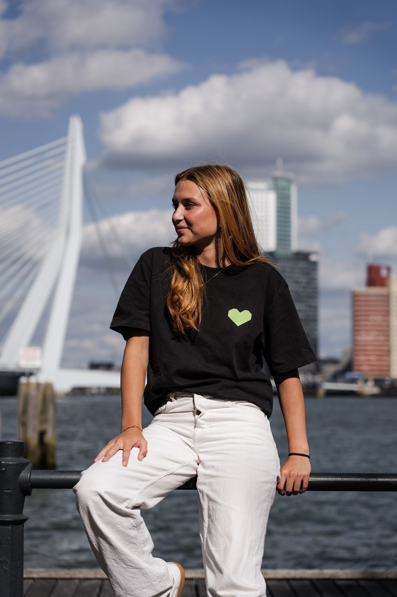 Oversized T-shirt met opdruk “YOU NEVER WALK ALONE” en illustratie van De Kuip, Erasmusbrug en skyline van Rotterdam in groen-rood kleurenpalet.