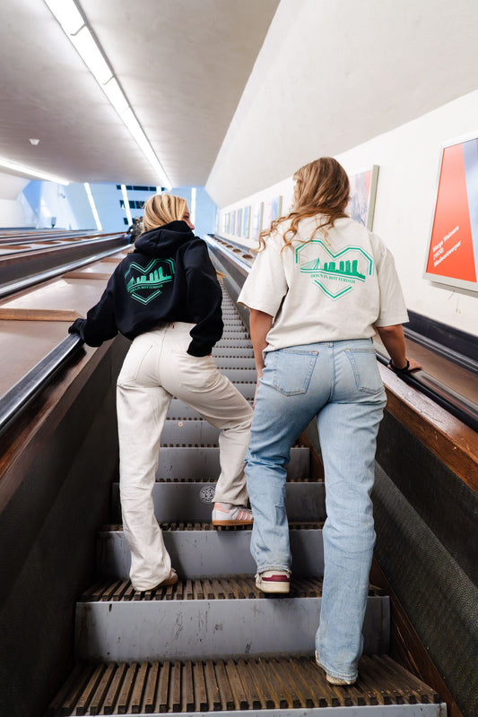 "Groen-wit ontwerp van een gebroken hart met skyline van Rotterdam en de tekst 'BØRN IN RØTTERDAM' eronder, gedrukt op een oversized TRØBL hoodie."