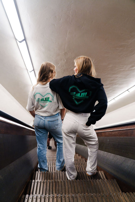 "Groen-wit ontwerp van een gebroken hart met skyline van Rotterdam en de tekst 'BØRN IN RØTTERDAM' eronder, gedrukt op een oversized TRØBL hoodie."